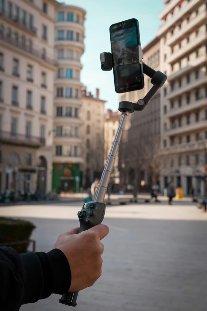 A person vlogs in a city with a smartphone and gimbal stabilizer.